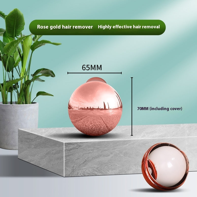 A reflective rose gold, 65mm spherical pet hair remover on a stone surface, featuring an internal white sticky ball.