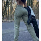 High-waisted olive green cargo pants with side pockets and utility style, worn in an outdoor, wooded setting.