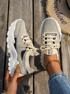 Beige and gray breathable flyknit mesh sneakers with white chunky soles and lace-up closure on a wooden background.