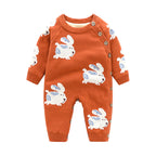 Rust-orange knitted baby romper featuring white rabbit patterns, side button closure, and ribbed cuffs.