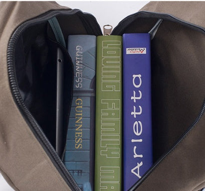 Open brown canvas backpack showing spacious interior with a tablet and three books inside.