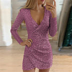 A woman wears a sparkly, long-sleeve, berry-pink sequin mini dress with a deep V-neck and an irregular wrap-style hem.