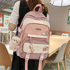 A person wears a pink and white Korean-style nylon backpack with character patches and a plush bear keychain.