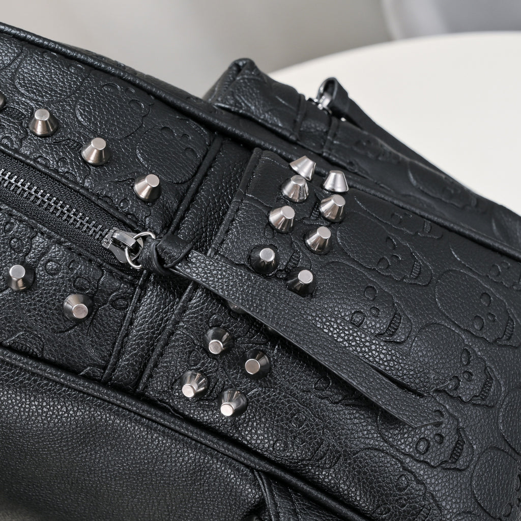Black soft leather backpack with embossed skull patterns and silver metal rivet studs. Zipper closure visible.