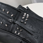Black soft leather backpack with embossed skull patterns and silver metal rivet studs. Zipper closure visible.