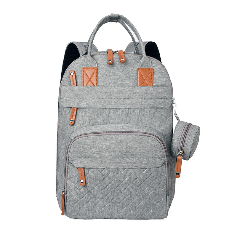 Grey multi-functional backpack with brown accents, top handles, quilted front pocket, and matching small pouch.