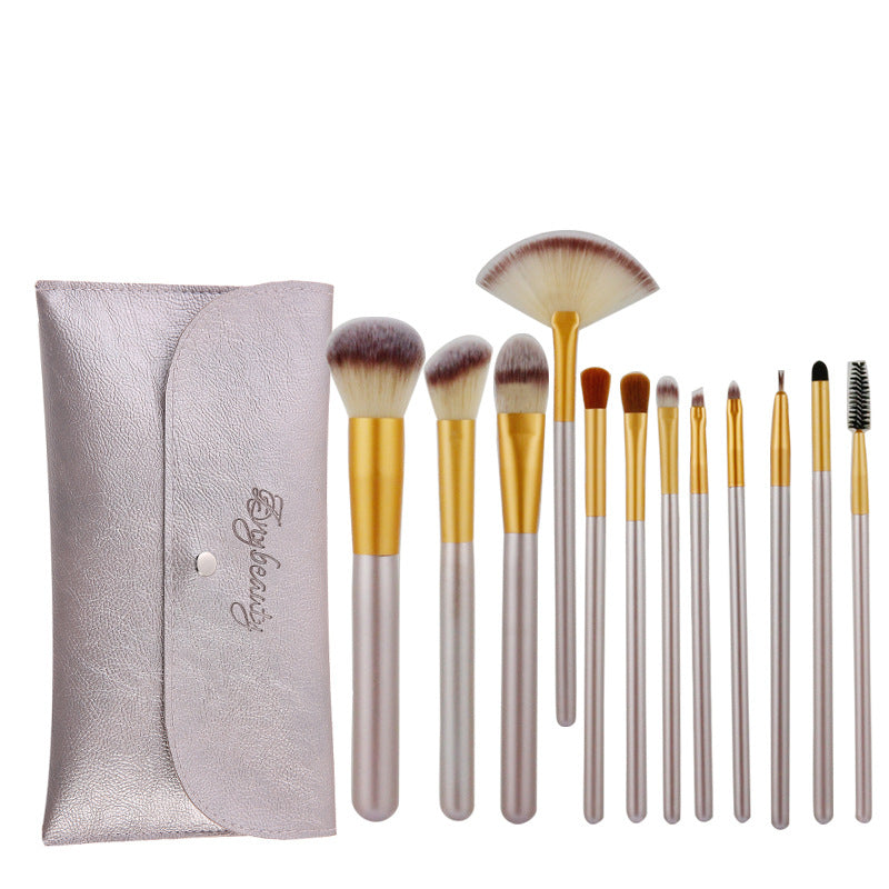 Set of 12 champagne-colored synthetic makeup brushes with gold ferrules and creamy bristles, includes a matching pouch.