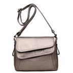 Metallic silver soft leather crossbody bag with an adjustable strap, fold-over flap, and structured silhouette.
