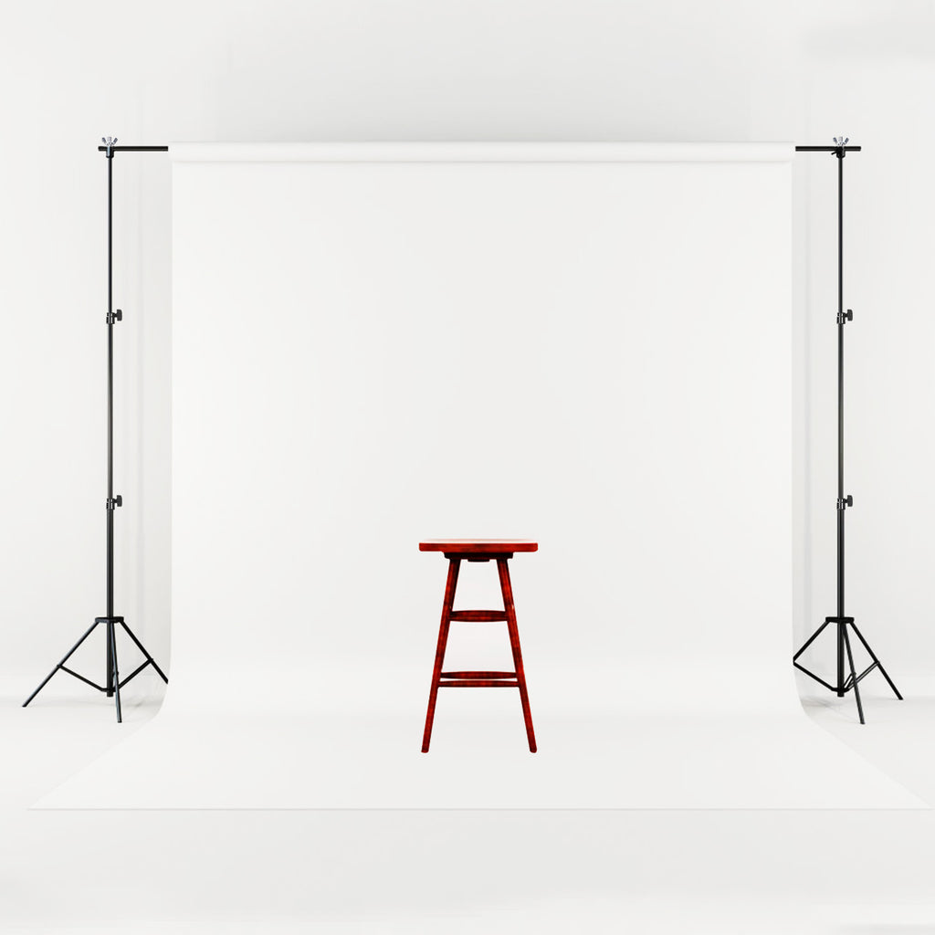 Adjustable black metal backdrop stand holding a seamless white fabric screen with a wooden stool in the center.