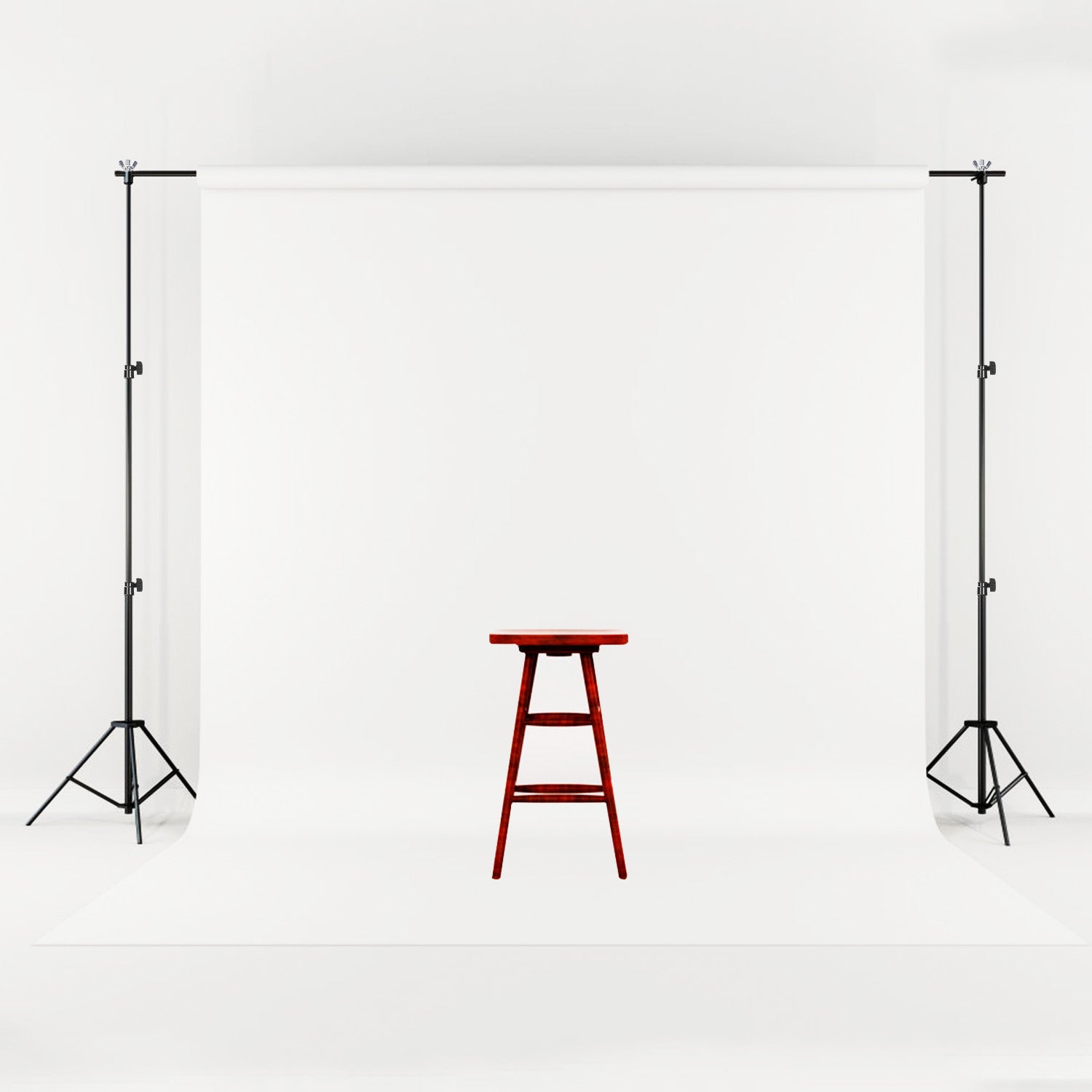 Adjustable black metal backdrop stand holding a seamless white fabric screen with a wooden stool in the center.