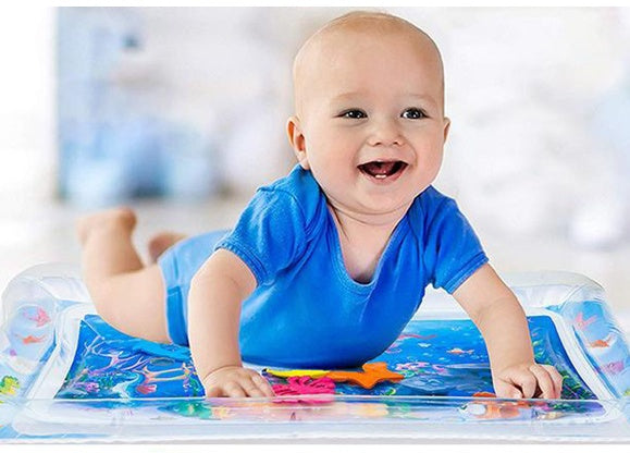 Smiling baby in blue onesie on a clear, inflatable water play mat with colorful, floating sea creature toys inside.