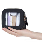 Small, square black PU leather cosmetic bag with a transparent window, held in hand, showing beauty products inside.
