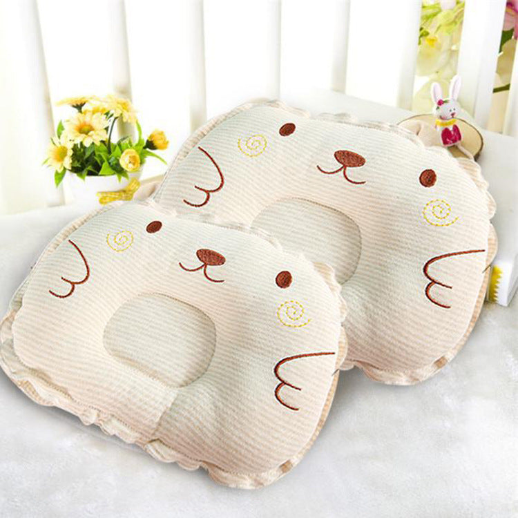 Two beige, textured baby pillows with embroidered animal faces and a center head-support indentation.