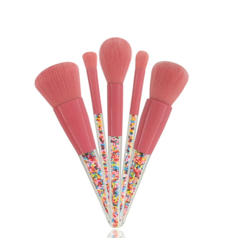 Digitaldistribution375 makeup brush set with pink bristles and clear handles filled with colorful candy sprinkles.