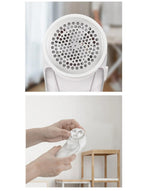 White handheld lint remover with a circular mesh head and internal blades, being assembled by hands.