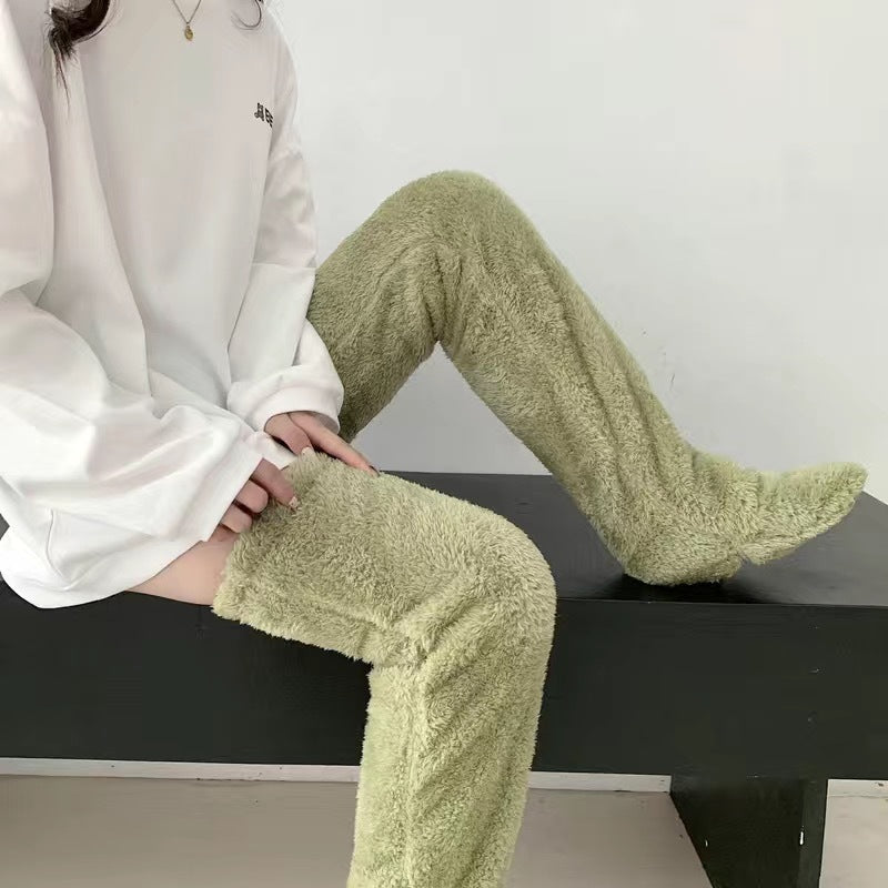 Person wearing sage green, fuzzy, fleece-like over-the-knee leg warmers for cozy indoor warmth.