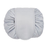 Light gray round, quilted cosmetic bag with a central flap closure and drawstring-style gathered fabric sides.
