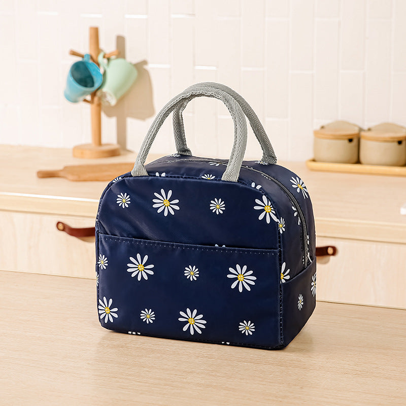 Navy blue waterproof lunch bag with white daisy print, grey handles, and insulated interior on a kitchen counter.