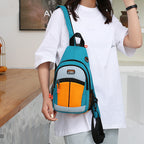 Woman wearing a teal, orange, and grey crossbody sling backpack with a USB port and mesh side pocket.