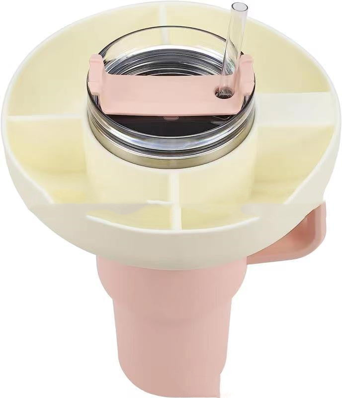 Cream-colored, 4-compartment silicone snack ring attached to a tumbler with a pink lid and straw, white background.