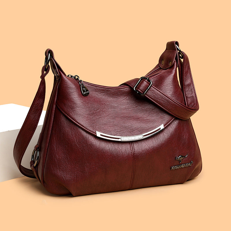 Maroon, soft leather women's shoulder bag with a crescent silver metal accent and adjustable strap.
