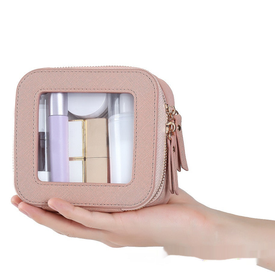 Small, pink, textured PU leather cosmetic bag with a transparent window, zipper closure, and visible beauty products.