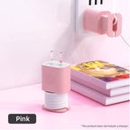 Pink silicone protective case and cable winder for Apple USB-C power adapters, shown organized on a white desk.