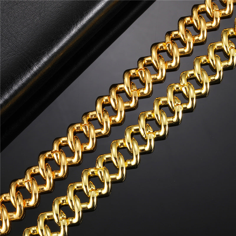 Gold-tone metal Cuban link chain featuring thick, interlocking polished links on a dark reflective background.