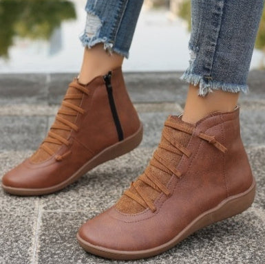 Brown faux leather ankle boots with lace-up fronts, side zippers, and flat soles worn with distressed blue jeans.