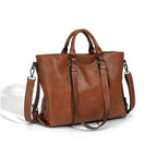 A large, soft brown faux leather tote bag with dual handles, an adjustable shoulder strap, and dark metal hardware.