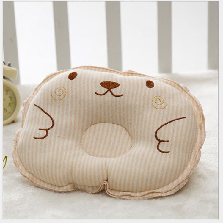 Beige striped baby pillow with a cute bear face embroidery and a center head-support dip on a soft white surface.