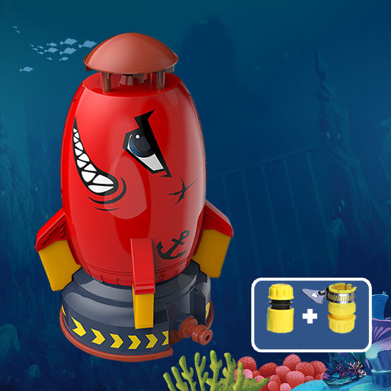 Red rocket water sprinkler with shark-face design, yellow fins, and gray base, plus yellow hose connectors.