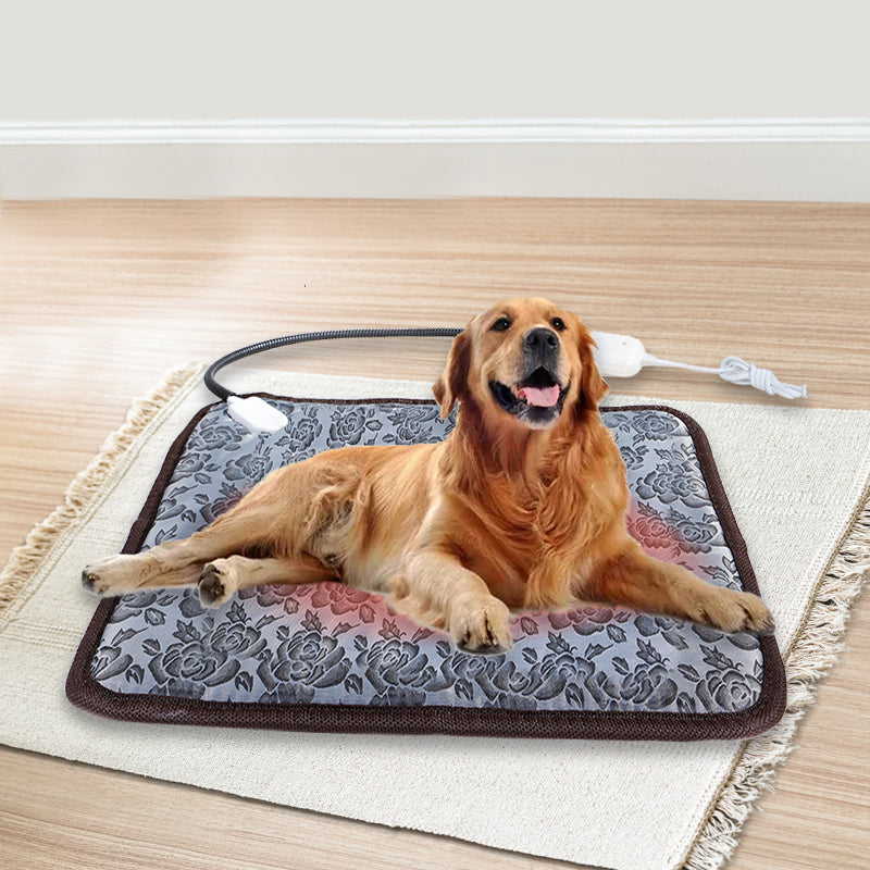 Golden retriever resting on a gray, floral-patterned electric pet heating pad with a chew-resistant cord.