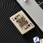 Gold metal windproof lighter featuring a King of Spades playing card design, sitting on a dark ribbed surface.