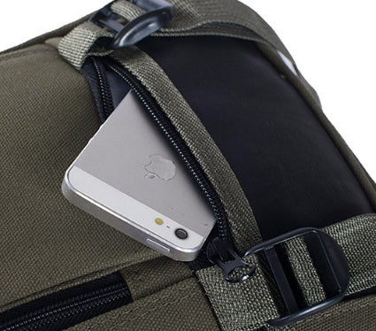 Close-up of an olive green canvas backpack featuring a zippered pocket holding a silver smartphone.