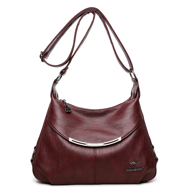 Burgundy soft leather shoulder bag with an adjustable strap, silver hardware accent, and kangaroo logo emblem.