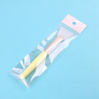Silicone facial mask brush with a yellow handle, rose gold ferrule, and white head, packaged in a clear plastic sleeve.