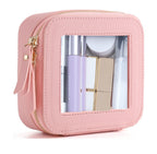Small, square pink PU leather cosmetic bag with a transparent window, gold zipper, and assorted beauty products inside.