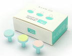 Three colorful grinding heads for baby electric nail trimmers next to their white and turquoise branded storage box.