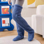 Plush blue fleece over-the-knee leg warmers covering gray leggings, providing cozy indoor warmth.