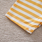 Close-up of a soft yellow and white striped baby cotton jumpsuit sleeve with white snap buttons.