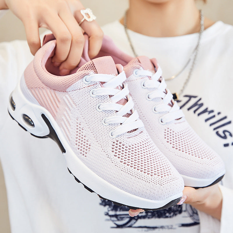 A woman holds blush pink knit running shoes with white laces, white midsoles, and air-cushioned heels.