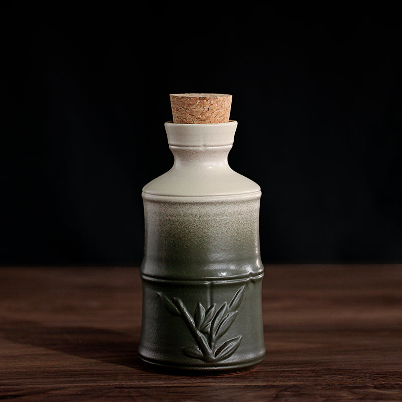 Ceramic sake bottle with a white-to-green gradient finish, bamboo relief detail, and a natural cork stopper.