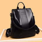 Black soft leather women's travel backpack with a top handle, adjustable straps, and a kangaroo logo on a tan background.