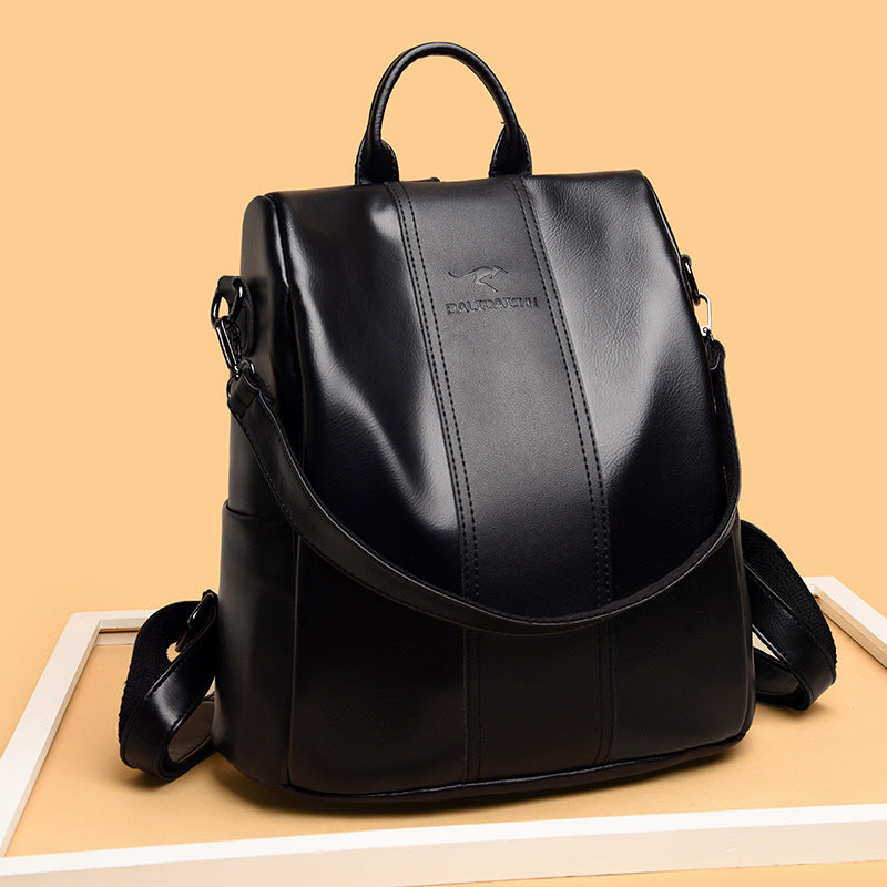 Black soft leather women's travel backpack with a top handle, adjustable straps, and a kangaroo logo on a tan background.