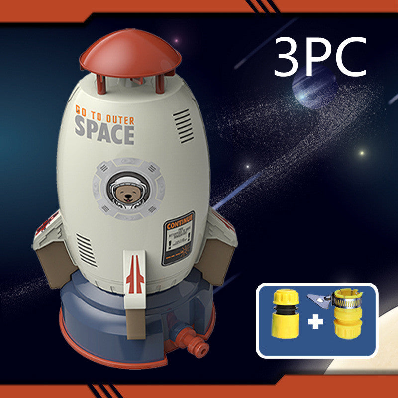 White and blue plastic rocket sprinkler toy with an astronaut bear graphic, plus hose attachments.