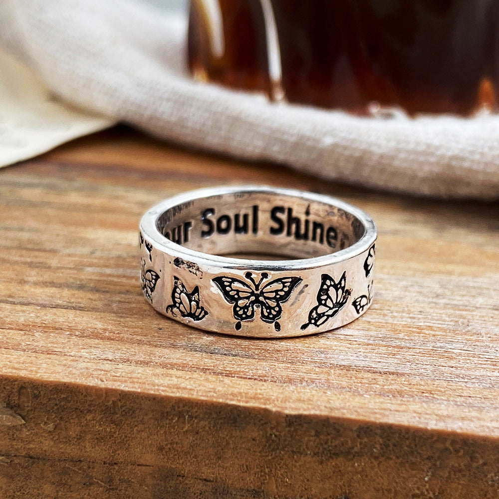 Silver ring featuring etched butterfly motifs on the outer band and the engraved phrase "Your Soul Shine" inside.