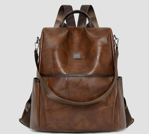 Minimalist brown faux leather backpack with stitched panel design, adjustable straps, and a front pocket.