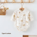 Cream-colored long-sleeve cotton newborn baby romper with an all-over cute bear print, hanging on a wooden hanger.