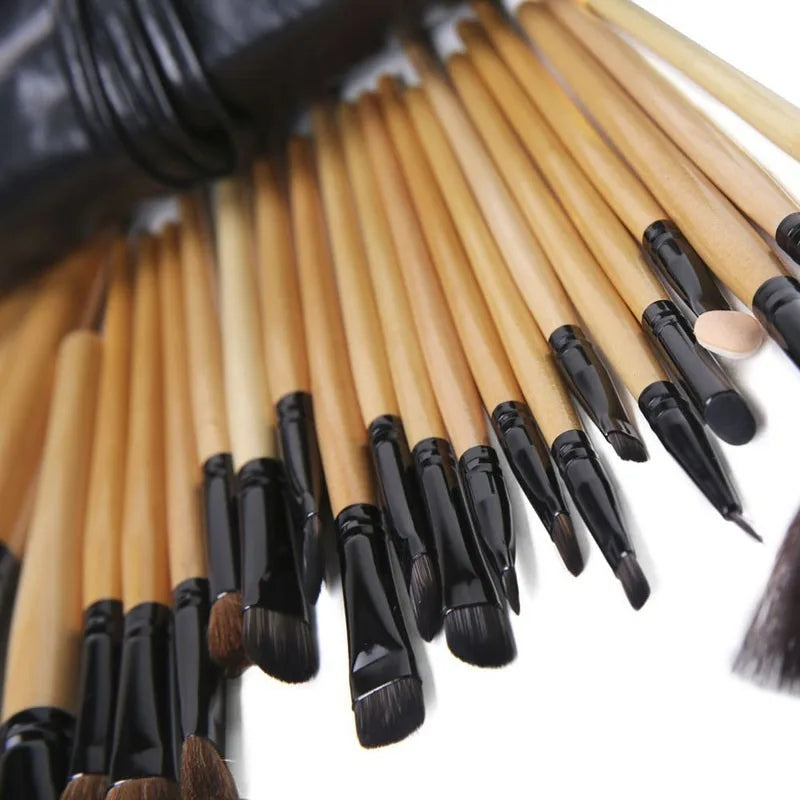 Set of 24 professional makeup brushes with light wood handles, black ferrules, and soft bristles in a black carry case.